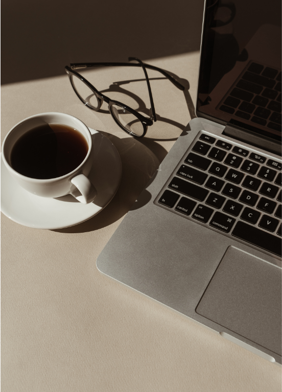 A laptop and coffee cup on a warm-toned desk