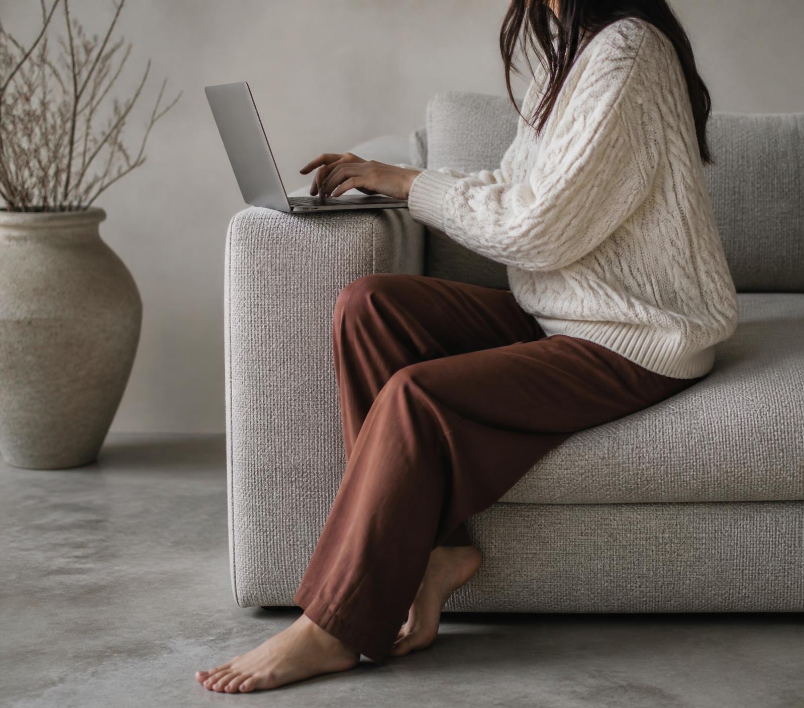 Jacqueline working on a laptop on a sofa in a calm, light-filled room